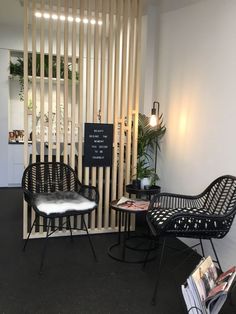 two black chairs sitting next to each other in front of a white wall with wooden slats