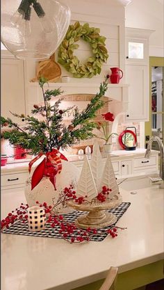 a kitchen counter with christmas decorations on it and a vase filled with trees in the center