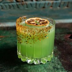 a green cocktail garnished with orange and sprinkles on the rim