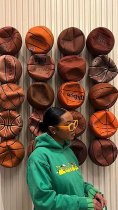 a woman standing in front of a wall with basketballs on it