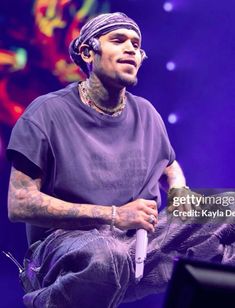 a man sitting on top of a stage wearing a bandana and holding a microphone