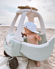 a baby sitting in a toy boat on the beach