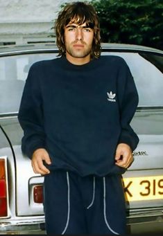 a man standing in front of a car with his hands on his hips and wearing sweatpants