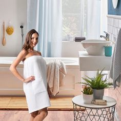 a woman in a white towel standing next to a bath tub