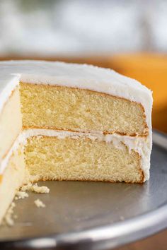 a close up of a slice of cake with white frosting on a silver plate