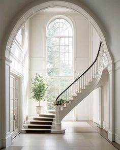 an arched doorway with stairs leading up to the second floor and potted plant on the far wall