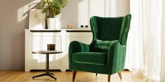 a green chair sitting in front of a window next to a table with a potted plant on it