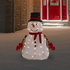 a lighted snowman in front of a red door