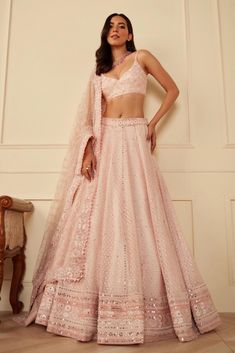 a woman in a pink lehenga and matching crop top is posing for the camera