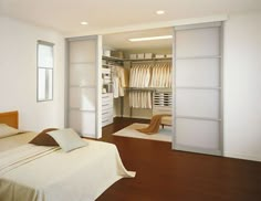 a bedroom with a bed and closets in the corner, next to a window