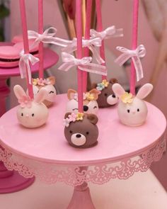 some pink candles are sitting on a table with little animals in them and bows tied to them