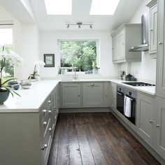 a white kitchen with wood floors and skylights