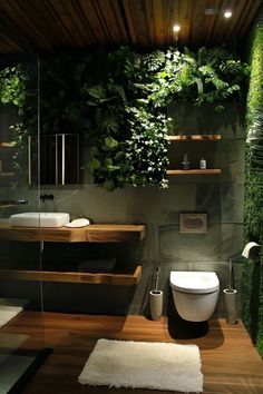 a bathroom with plants growing on the wall and wooden flooring, along with a white rug