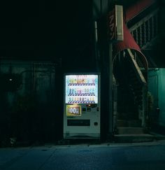 a vending machine sitting on the side of a road next to a building at night