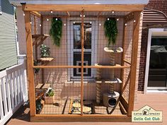 an outdoor cat house made out of wood and wire with plants growing on the roof