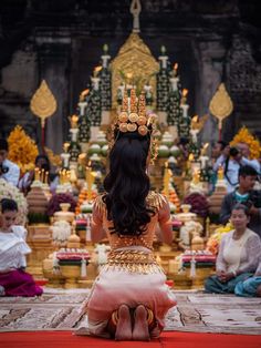 a woman sitting on the ground in front of a group of people wearing thai garb