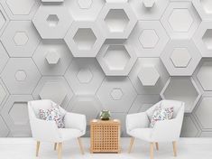 two white chairs sitting next to each other in front of a wall with hexagonal tiles