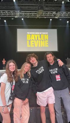 three people posing for a photo in front of a stage with a screen behind them