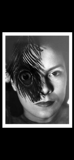 a black and white photo of a woman's face with feathers on her eyes