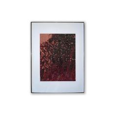 an abstract painting with red and black colors in a white frame against a white wall