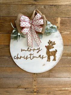 a wooden plaque with the words merry christmas written on it and a bow hanging from the front