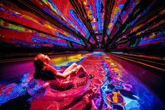 a woman sitting on an inflatable tube floating down a river filled with colorful lights