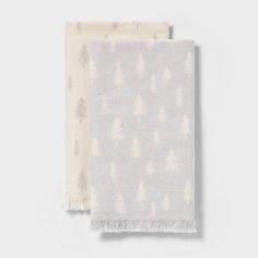 two white and grey towels with trees printed on the front, one is folded up