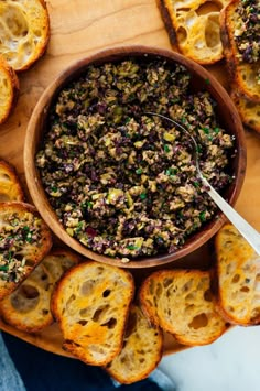 a wooden bowl filled with food next to slices of bread