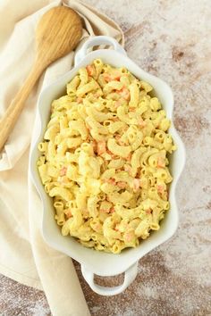 a bowl filled with macaroni and cheese next to a wooden spoon