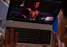 a man sitting in front of a laptop computer with spiderman on the monitor screen