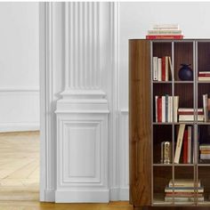 a bookshelf filled with lots of books on top of a hard wood floor