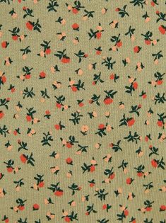 an apple print fabric with small red and black flowers on green background, closeup