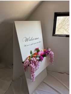 there is a welcome sign with flowers in it