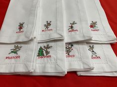 six embroidered christmas napkins on a red table