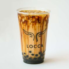 an iced coffee cup with caramel and chocolate swirls on the bottom, sitting on a white surface