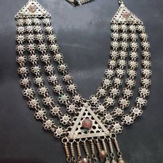 * This long, rusty silver necklace is embellished with fine floral elements, assembled in strings, making it one piece. The pendant is adorned with antique stone, dangling tassels, and floral motifs carved within the piece. This exclusive piece is an inspired style by Afghani kuchi ornaments, worn by the women of tribes as integral part of their cultural practices. You can pair this necklace with any traditional or trendy outfit, and it would get along any of the chosen fashion statements. Note: Bohemian Necklaces With Intricate Design For Festivals, Bohemian Necklaces With Traditional Patterns For Festivals, Bohemian Long Temple Necklace For Festivals, Bohemian Long Temple Necklace For Wedding, Bohemian Necklace With Traditional Patterns As Gift, Bohemian Necklace With Traditional Patterns For Gift, Bohemian Multicolor Temple Necklace With Intricate Design, Bohemian Multi-strand Necklaces For Wedding, Bohemian Multi-strand Necklace For Wedding