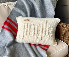 a crocheted pillow sitting on top of a chair next to a blanket and pillows