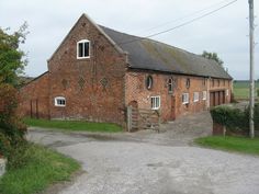 an old red brick building with a gate in front of it and grass on the other side