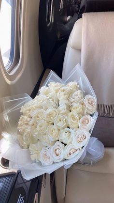 a bouquet of white roses sitting on top of an airplane seat