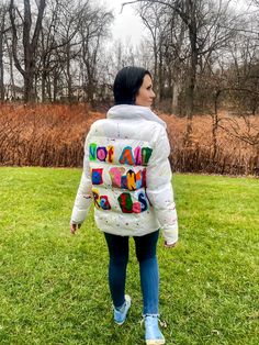 "We've transformed a basic white puffer jacket into this piece of wearable art that carries an artistically profound message: \"not all who wander are lost.\" This jacket has been thoughtfully upcycled, featuring the timeless phrase in a newspaper clipping style hand painted on the back in a spectrum of vibrant hues. It's a subtle nod to the spirit of exploration and self discovery. Embrace its uniqueness and wear it as a personal statement, allowing the jacket to speak for itself in its understated beauty. With a blend of repurposed fashion and individual expression, this piece invites you to wander freely while making a sustainable fashion choice. Fashion Nova Medium 100% Nylon" Painted Puffer Jacket, Artistic Winter Outerwear For Streetwear, Artistic Winter Streetwear Outerwear, White Patchwork Hooded Outerwear, Functional Recycled Polyester Puffer Outerwear, Recycled Polyester Puffer Outerwear, Winter Cotton Outerwear With Graffiti Print, White Puffer Jacket, White Puffer