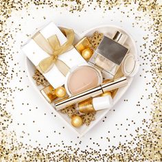 a heart shaped box filled with cosmetics and christmas decorations on top of a gold sequin background