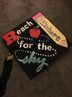 a graduation cap that has been decorated with words and an apple on the front, which reads reach for the sky