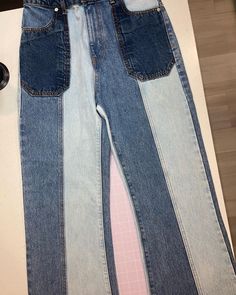 two pairs of jeans sitting on top of a table