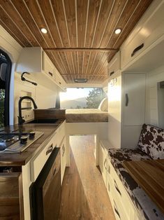 the interior of a camper with wood flooring and white cabinets is shown in this image