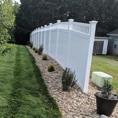 a large white fence next to a lush green yard