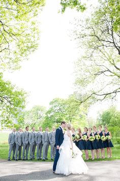 a bride and groom kissing in front of their wedding party