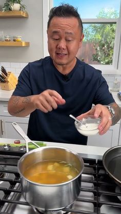 a man is stirring something in a pot on the stove top while holding a spoon