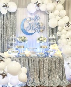 a table with white balloons, silver and blue decorations and stars on the wall behind it