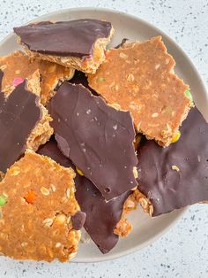 a white plate topped with pieces of chocolate covered cookies next to candy canes and sprinkles