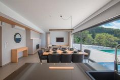 a dining room and kitchen area with large windows overlooking the pool in the back yard